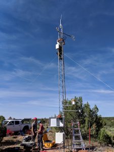 Photo from setup of a Rapid Response Flux system being set up in the field. Ryan Bares and Steve Kannenberg are standing on the ground, while Dave Eriksson is climbing up on the tower scaffolding at about 15 feet high.