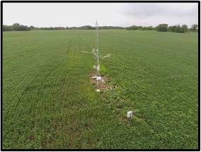 Photo of a ca. 20ft high flux tower amid a green field.
