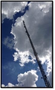 photo of a tall scaffolding tower against a backdrop of a cloud in a blue sky.
