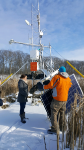2 Researchers adjusting a flux tower while standing on a frozen lake
