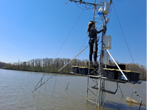 Researcher Justine Missik climbing on a flux tower in the middle of a lake
